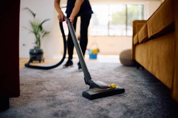Home close up of woman vacuuming while working professional cleaner.